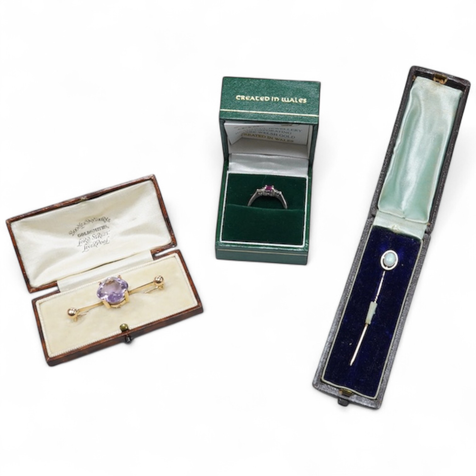 A cased late Victorian 9ct and single stone amethyst set bar brooch, 45mm, a cased yellow metal and single stone white opal set stick pin and a modern 18ct white gold, ruby and diamond cluster ring, size L/M.